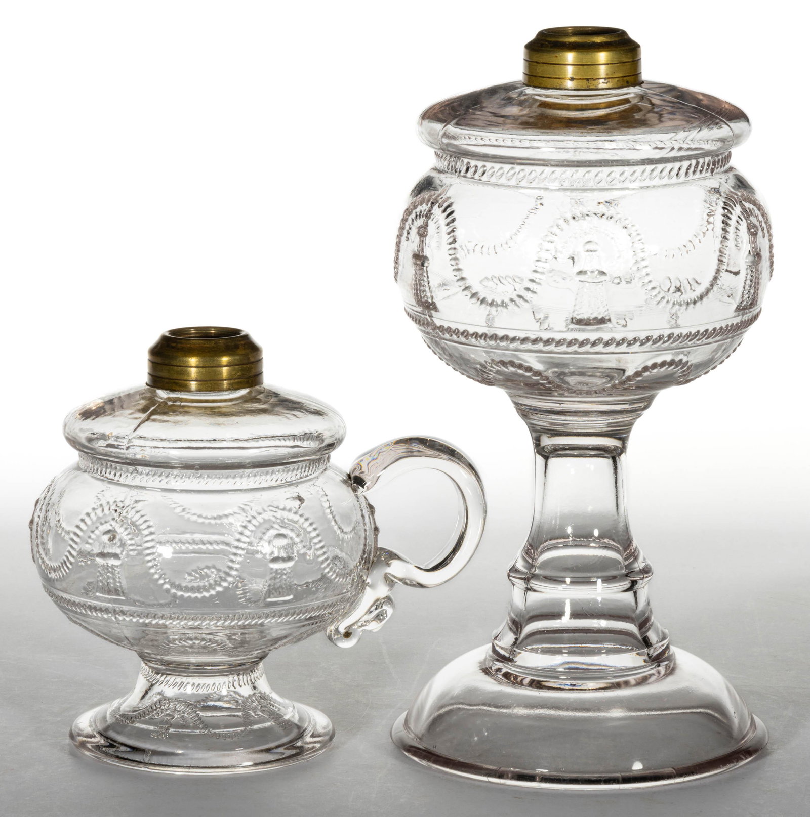 CORD AND TASSEL FOOTED KEROSENE LAMPS, LOT OF TWO: CORD AND TASSEL FOOTED KEROSENE LAMPS, LOT OF TWO, colorless, comprising a stand lamp and a finger lamp, each having a period brass collar. La Belle Glass Co./Central Glass Co. Fourth quarter 19th/ear