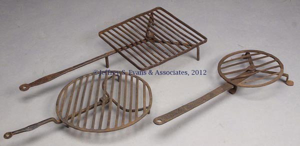 THREE WROUGHT-IRON HEARTH BROILERS: THREE WROUGHT-IRON HEARTH BROILERS, comprising two circular and one square, each with revolving rack raised on three feet. 19th and possibly 20th century. 22" to 27" L. Provenance: Estate collection o