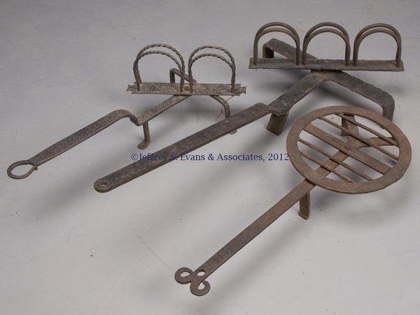 THREE WROUGHT-IRON HEARTH ARTICLES: THREE WROUGHT-IRON HEARTH ARTICLES, comprising two revolving toasters and a broiler, each raised on three feet. Broiler stamped "C.H.C." on top of handle. 19th and/or 20th century. 18" to 25" L. Prove