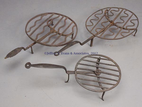 THREE WROUGHT-IRON HEARTH BROILERS: THREE WROUGHT-IRON HEARTH BROILERS, each with revolving rack raised on three feet. Probably 18th or 19th century. 19" to 24" L. Provenance: Estate collection of Dorothy and Marshall Jenkins.