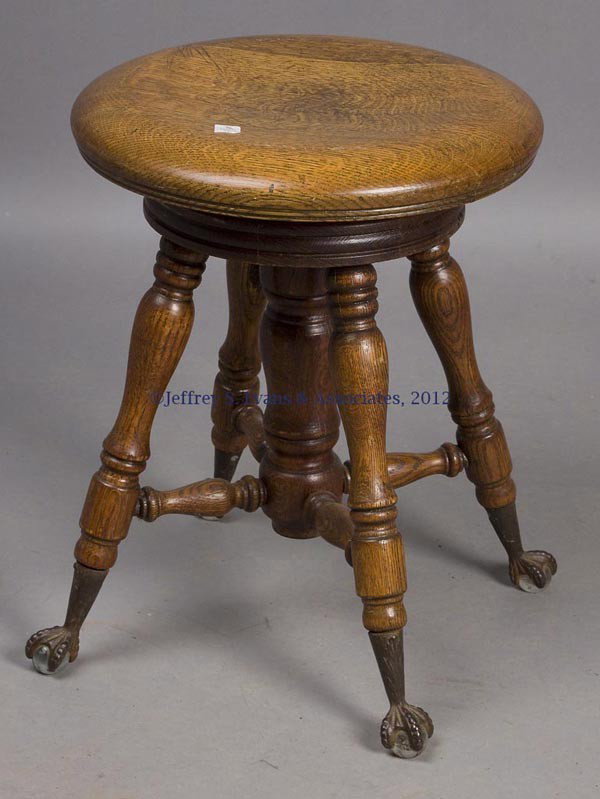AMERICAN LATE VICTORIAN OAK PIANO STOOL: AMERICAN LATE VICTORIAN OAK PIANO STOOL, adjustable seat, iron and glass ball and claw feet. Late 19th/early 20th century. 18 1/2" H. Provenance: Estate collection of Dorothy and Marshall Jenkins.