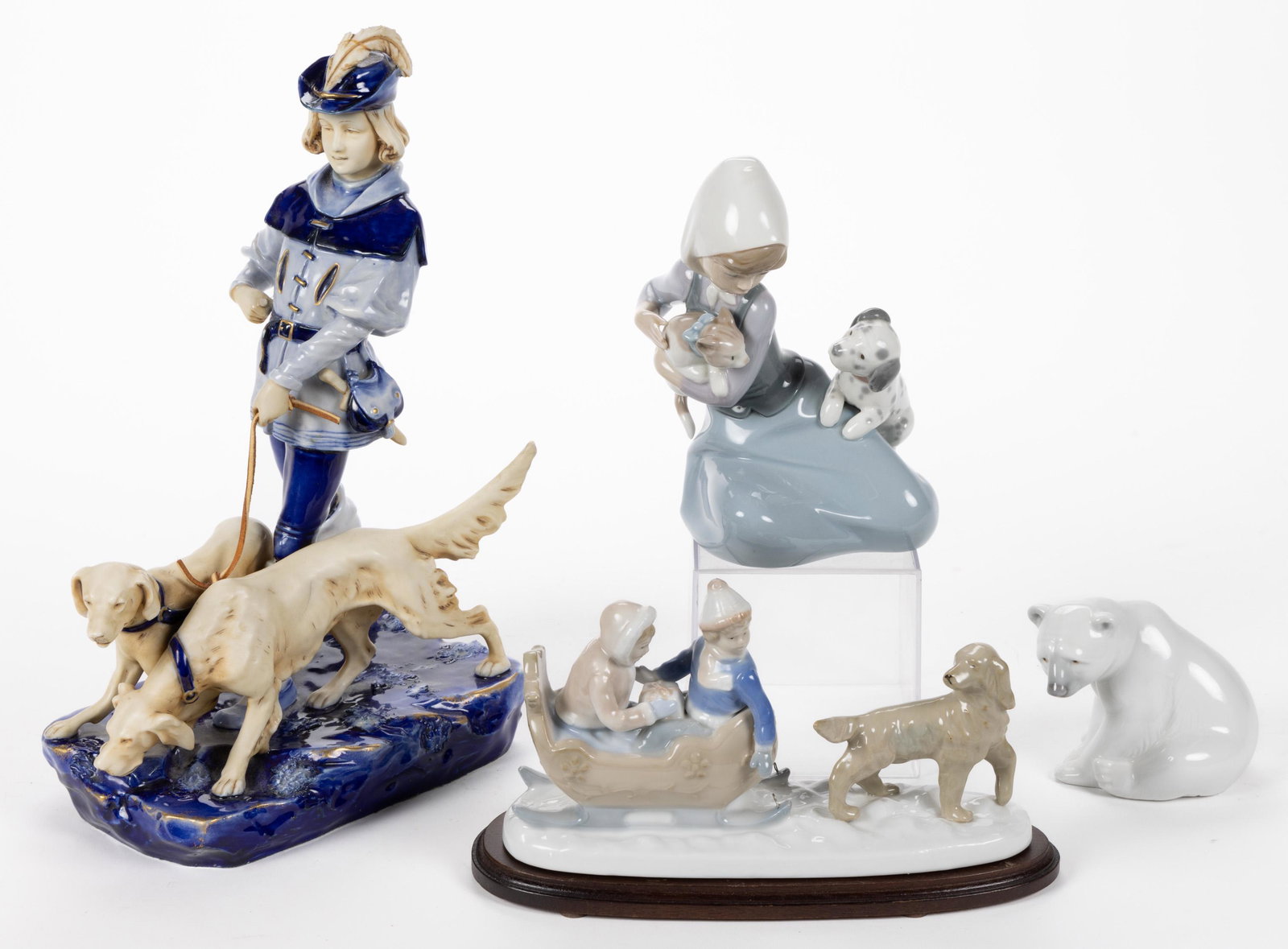 ASSORTED HAND-PAINTED PORCELAIN FIGURES, LOT OF FOUR: ASSORTED HAND-PAINTED PORCELAIN FIGURES, LOT OF FOUR, comprising a Royal Dux example featuring a young man wearing a Tyrolean hat and walking two dogs, two Lladro examples including a sitting pol