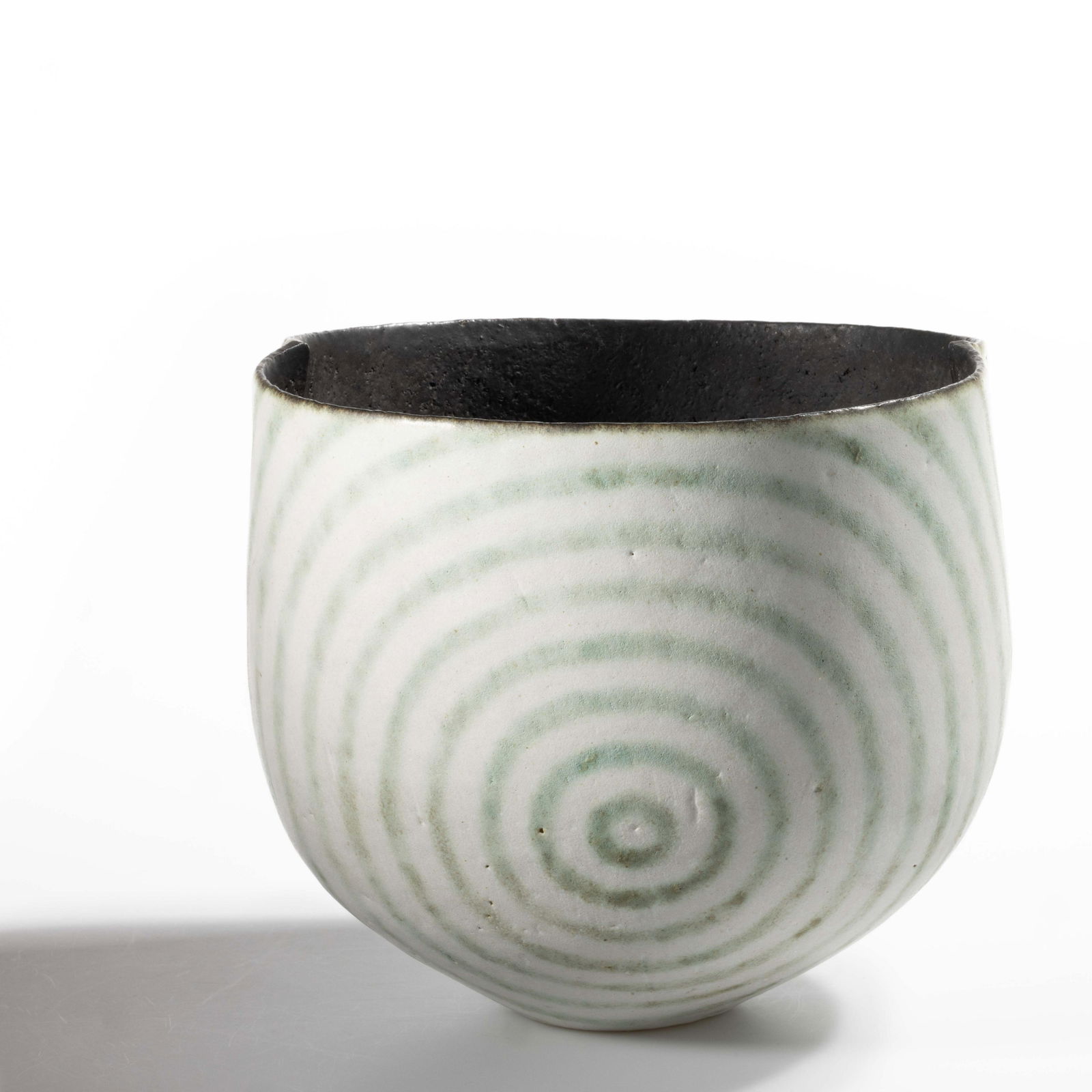 JOHN WARD (ENGLISH, 1938-2023) STUDIO POTTERY STONEWARE BOWL: JOHN WARD (ENGLISH, 1938-2023) STUDIO POTTERY STONEWARE BOWL, rounded form with two sides slightly indented, featuring a matte green and white bull's eye design. Impressed "JW"
