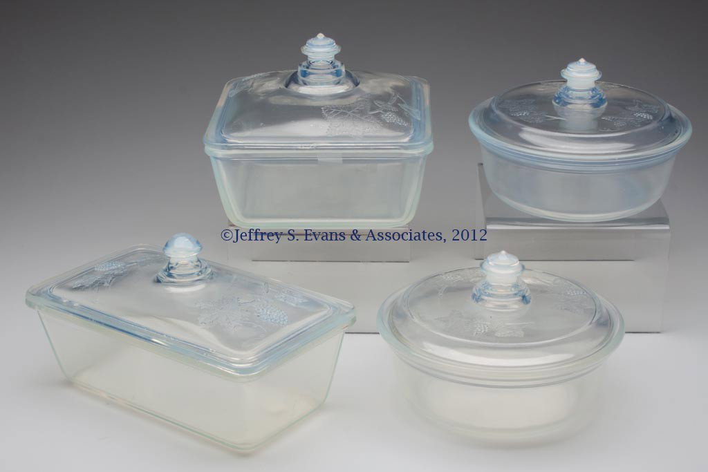 FRY KITCHENWARE COVERED DISHES, LOT OF FOUR: FRY KITCHENWARE COVERED DISHES, LOT OF FOUR, opalescent, each with embossed Grape cover, comprising #1928-9, #1935-7, and two #1938-7. H. C. Fry Glass Co. First half 20th century. Various sizes. Prove