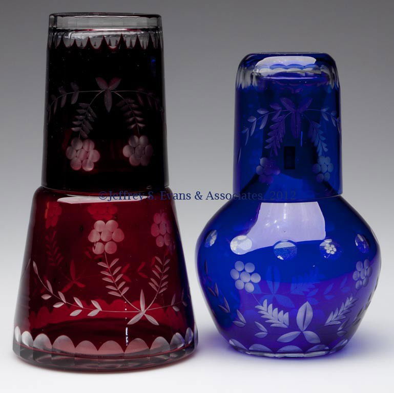 FLORAL CUT OVERLAY TUMBLE-UPS, LOT OF TWO: FLORAL CUT OVERLAY TUMBLE-UPS, LOT OF TWO, ruby and blue cut to colorless, each bottle polished under base. 20th century. 7" and 8 1/4" H. Provenance: Collection of Jack & Dorothy Jordan.
