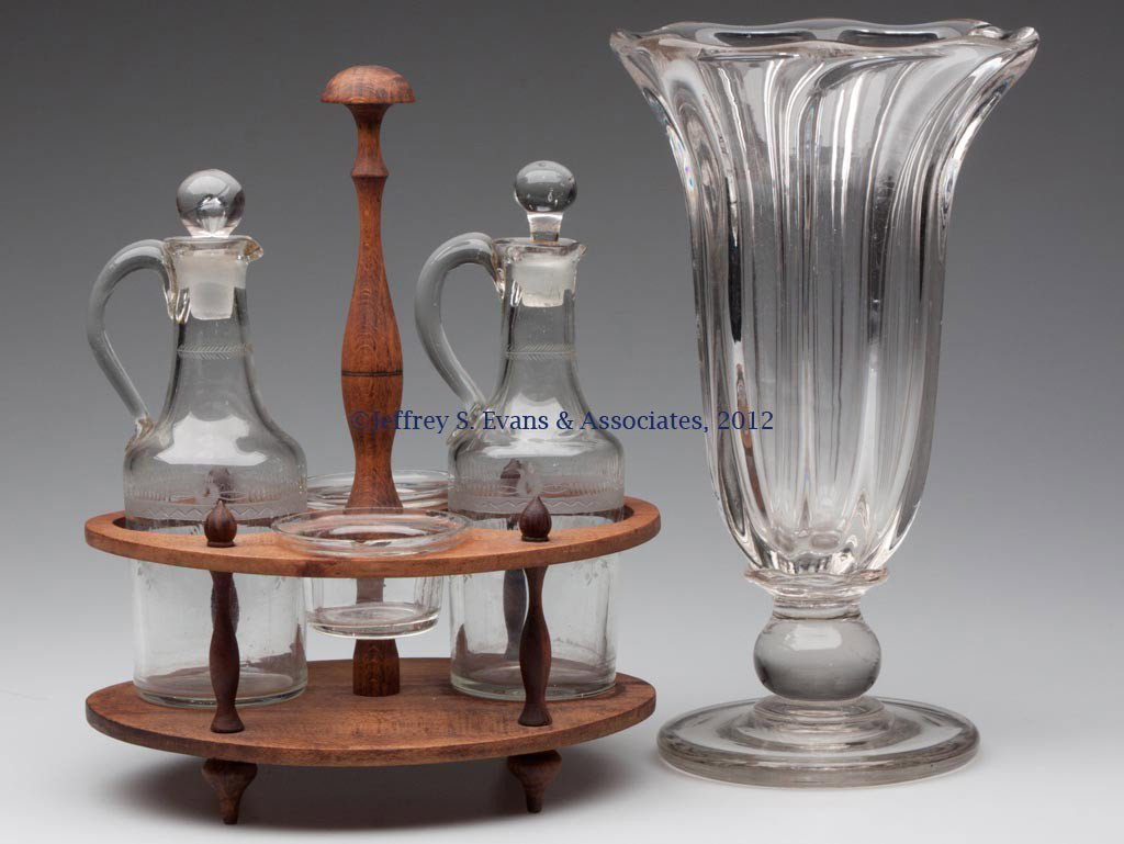EARLY BLOWN GLASS ARTICLES, LOT OF TWO: EARLY BLOWN GLASS ARTICLES, LOT OF TWO, comprising a pillar-molded celery vase with eight pronounced ribs and a polished pontil mark, and a condiment set with two engraved cruets and wooden stand. Pit