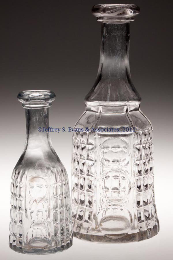 BLOWN-MOLDED WAFFLE AND THUMBPRINT DECANTERS, LOT : BLOWN-MOLDED WAFFLE AND THUMBPRINT DECANTERS, LOT OF TWO, colorless lead glass, comprising a three-pint example and a bitters bottle, each with applied bar lip and polished pontil mark. Third quarter 