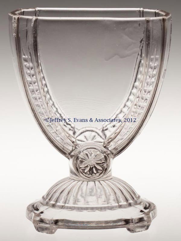 JUMBO - CANTON (RIBBED) SPOONER: JUMBO - CANTON (RIBBED) SPOONER, colorless, also with ribs under base and raised on four tabs. Canton Glass Co. Fourth quarter 19th century. 5" H. 5" H, 2 1/2" x 3 3/4" Provenance: Jerry Lynn Wood est