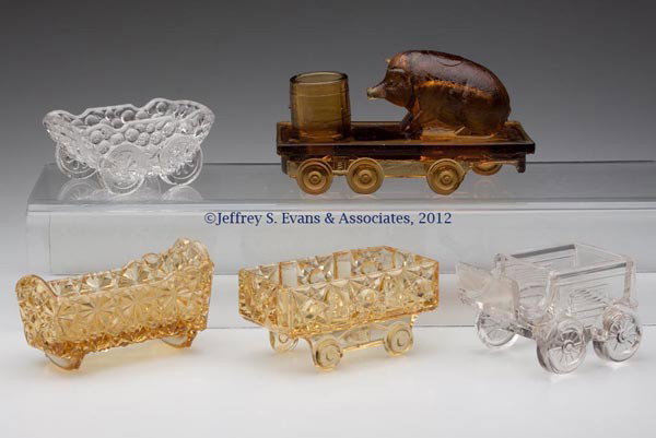 VARIOUS NOVELTIES, LOT OF FIVE: VARIOUS NOVELTIES, LOT OF FIVE, amber and colorless, comprising buggy, Stars and Bars railroad car, Daisy and Button cradle, and stage coach salt dips, and a Pig on Flat Car toothpick holder. Bellaire