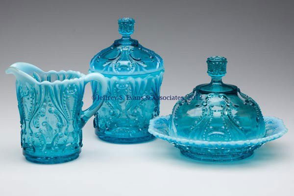 IDYLL THREE-PIECE TABLE SET: IDYLL THREE-PIECE TABLE SET, blue opalescent, comprising a butter dish, covered sugar bowl, and creamer. Jefferson Glass Co. First quarter 20th century. 5" to 7 " HOA. Provenance: Jerry Lynn Wood esta