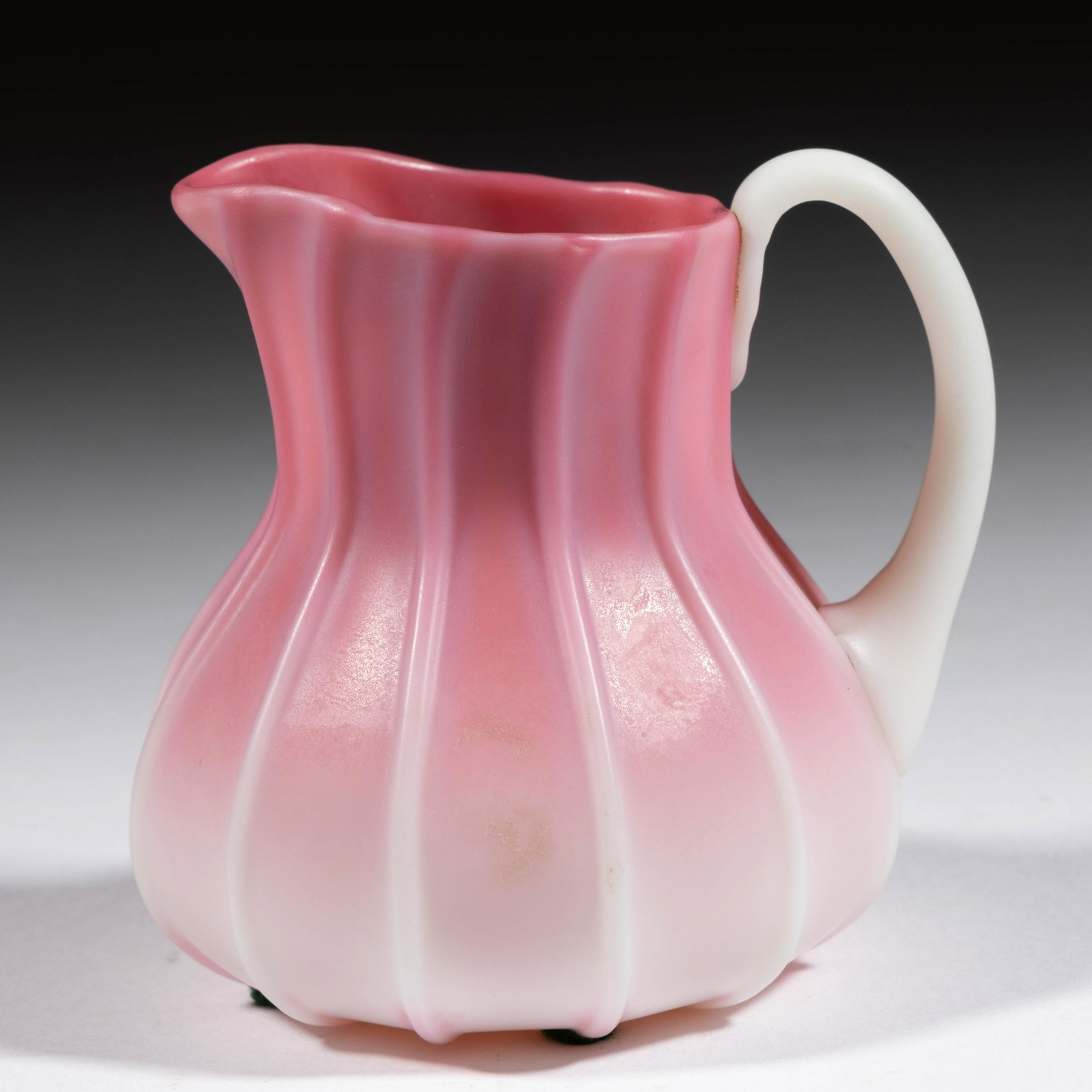 NEW ENGLAND PEACHBLOW RIBBED CREAMER: NEW ENGLAND PEACHBLOW RIBBED CREAMER, plush, baluster form with 12 vertical ribs, applied opal handle. New England Glass Co. Fourth quarter 19th century. 3 1/4" H. Literature: