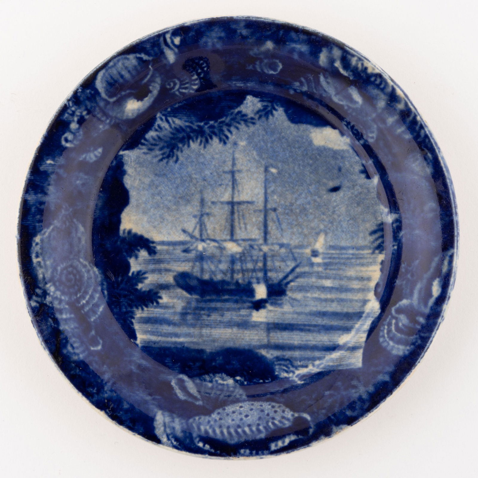 STAFFORDSHIRE BOAT / NAUTICAL MOTIF TRANSFER-PRINTED CERAMIC CUP PLATE: STAFFORDSHIRE BOAT / NAUTICAL MOTIF TRANSFER-PRINTED CERAMIC CUP PLATE, featuring Frigate at Anchor, depicting a tall-masted ship with sails down, having partial border and rounded shoulder. Impressed