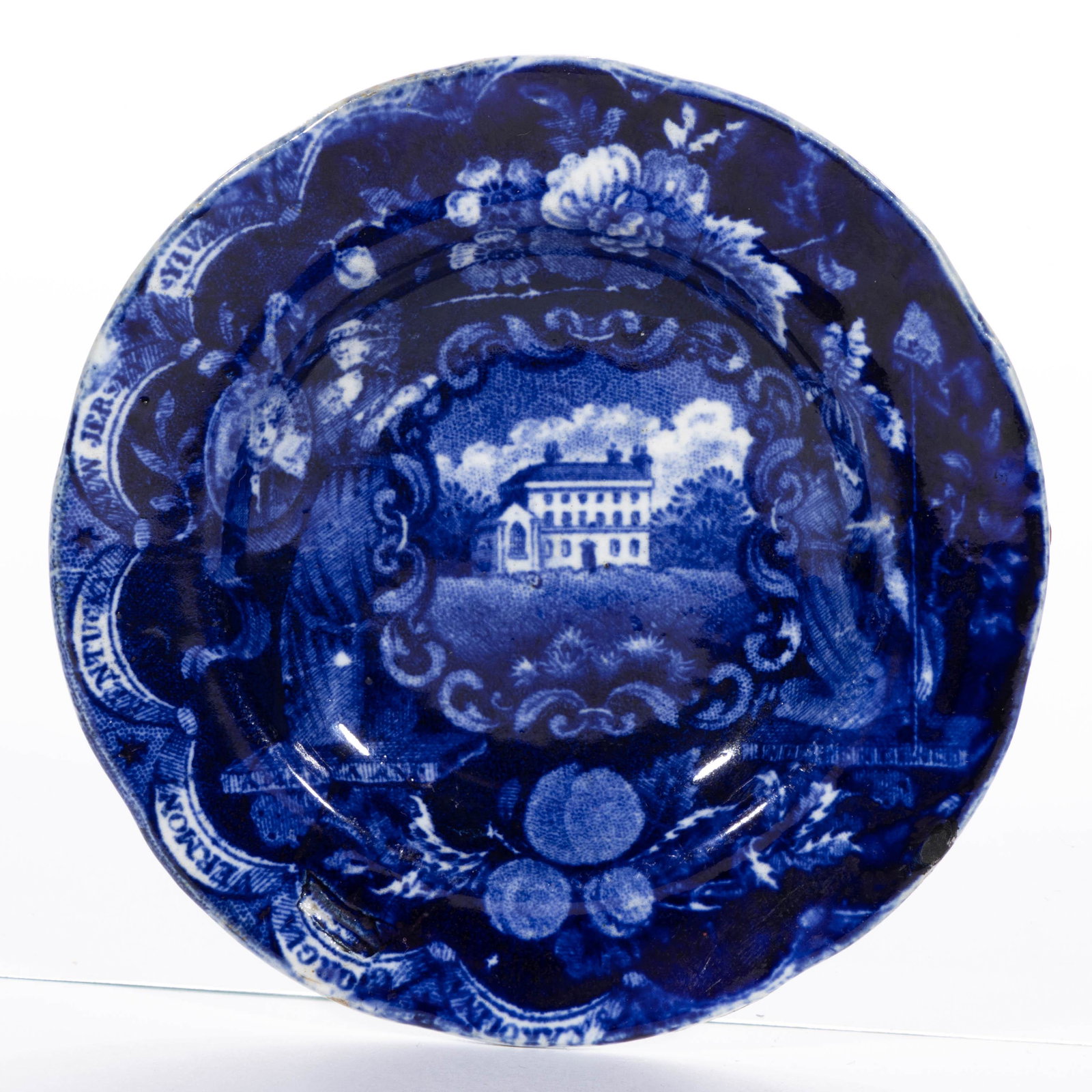 STAFFORDSHIRE AMERICAN HISTORICAL TRANSFER-PRINTED CERAMIC CUP PLATE: STAFFORDSHIRE AMERICAN HISTORICAL TRANSFER-PRINTED CERAMIC CUP PLATE, featuring a States series pattern, depicting St. Woolston's, Kildare, Ireland, flanked by patriotic female figures Justice and