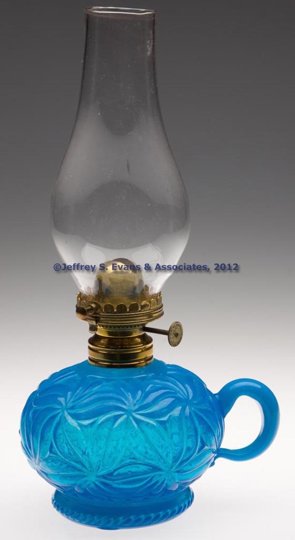 E. MILLER NO. 1 HINGED LIP BURNER: E. MILLER NO. 1 HINGED LIP BURNER, thumbwheel marked "E. MILLER & CO. / MADE IN U. S. A.", period lip chimney. Fitted on a translucent starch blue with light opalescence finger lamp with embossed flor