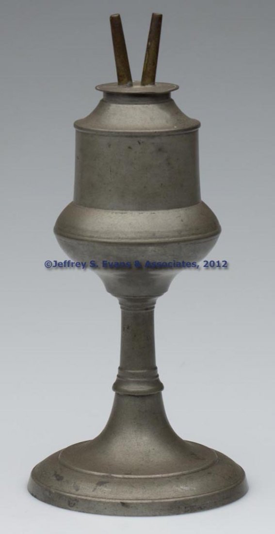PEWTER FLUID BURNING STAND LAMP: PEWTER FLUID BURNING STAND LAMP, acorn-form font supported on a ringed stem and circular weighted base, brass and pewter double-tube burner. Mid 19th century. 7 3/4" H, 4 1/4" D base. Literature: Font