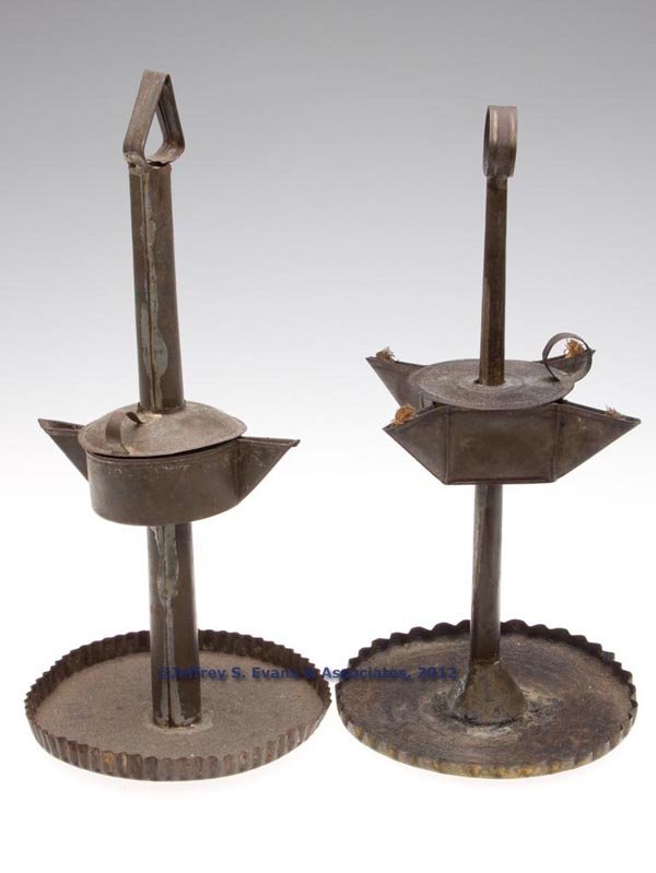 SHEET IRON GREASE / FAT LAMPS ON STANDS, LOT OF TW: SHEET IRON GREASE / FAT LAMPS ON STANDS, LOT OF TWO, comprising a circular form with double spouts and a pendant form with four spouts, each with a cover which slides up central shaft, ring finial, an