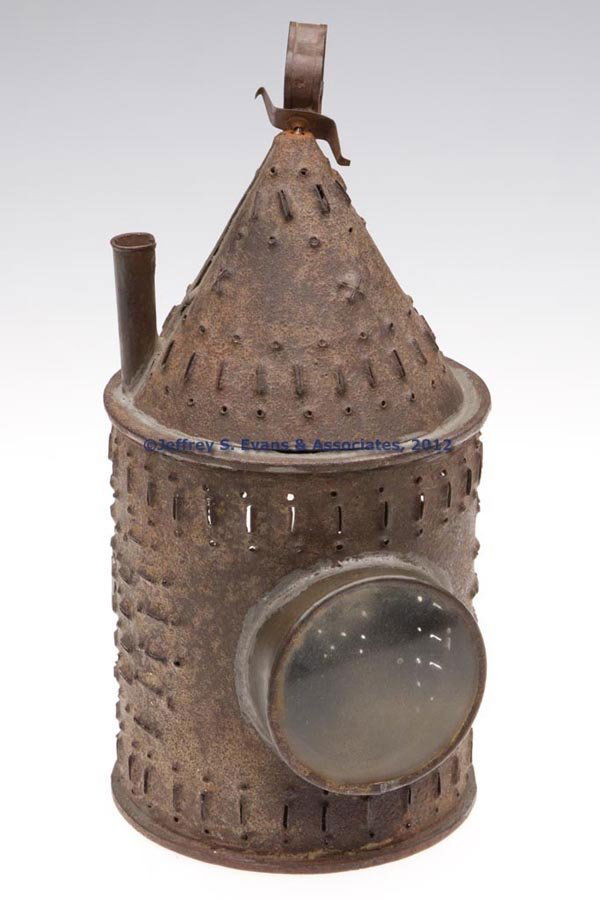 PIERCED AND PUNCHED SHEET IRON CANDLE LANTERN WITH: PIERCED AND PUNCHED SHEET IRON CANDLE LANTERN WITH DOUBLE BULLS-EYE LENS, traces of red paint, cylindrical form with conical-form top and strap triangular-form handle, hinged door with hasp, and a sin