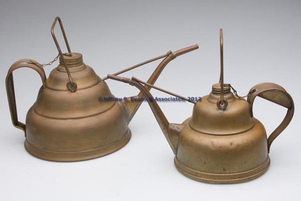 BRASS LAMP FILLERS, LOT OF TWO: BRASS LAMP FILLERS, LOT OF TWO, each with strap handle, bail handle and removable cover with connected chain, bases marked to underside for F. H. Lovell & Co. and National Metal Spinning & Stamping Co