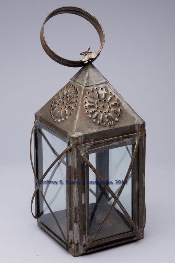 PUNCHED SHEET IRON CANDLE LANTERN: PUNCHED SHEET IRON CANDLE LANTERN, square form with large strap handle, top with sunburst and dot pattern on each side, colorless glass panes on each side with guards, one fitted in a sliding frame, r