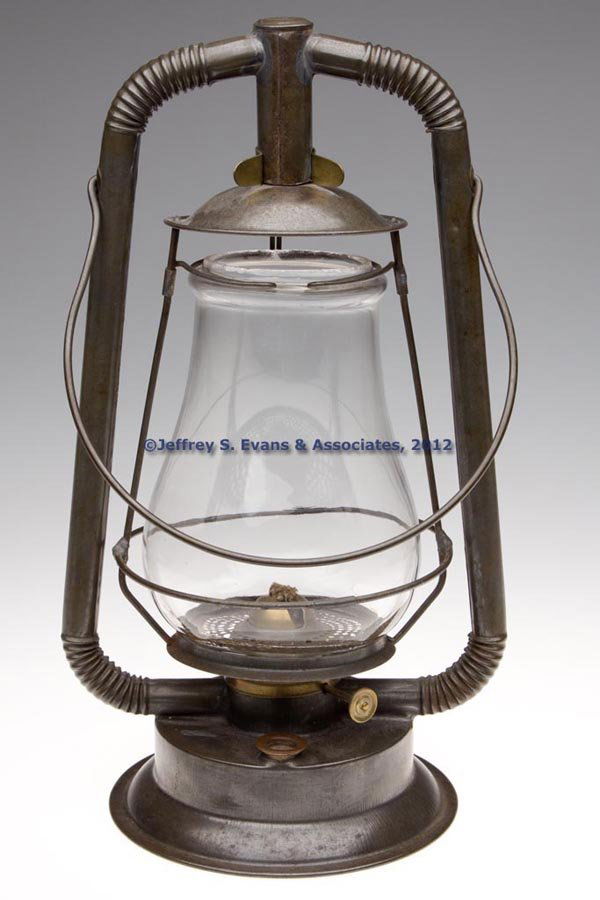 UNIDENTIFIED SHEET IRON HOT BLAST TUBULAR LANTERN: UNIDENTIFIED SHEET IRON HOT BLAST TUBULAR LANTERN, bail handle and corrugated tube arcs, tilt feature with brass clip on cap for securing, colorless globe embossed "18". Fitted with a brass burner. Fo