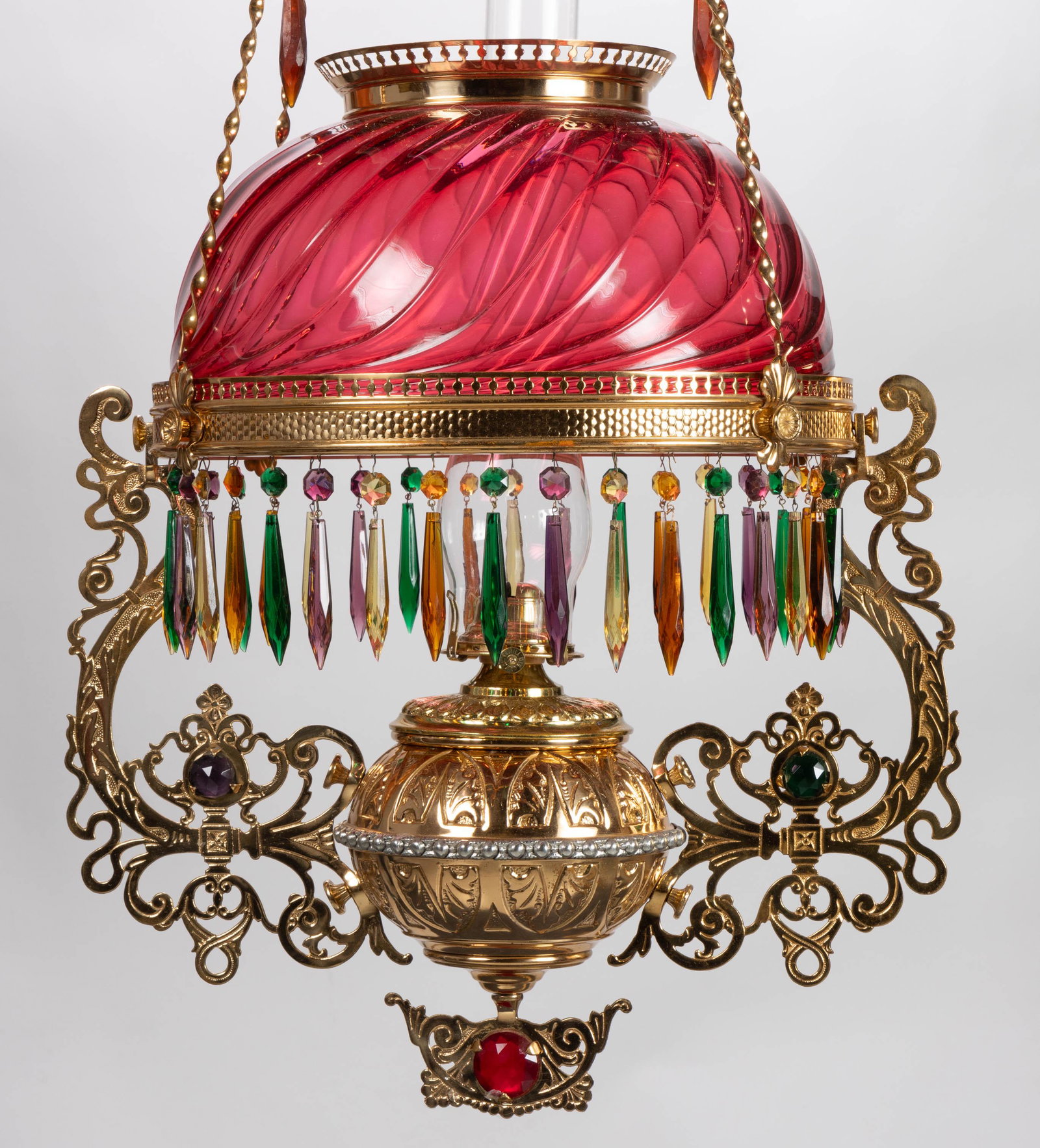 BRADLEY & HUBBARD SWIRLED GLASS AND JEWELED KEROSENE HANGING / LIBRARY LAMP: BRADLEY & HUBBARD SWIRLED GLASS AND JEWELED KEROSENE HANGING / LIBRARY LAMP, cranberry Swirled umbrella shade, copper finished Acanthus Leaf font tank with mixed-metal medial band fitted with a br