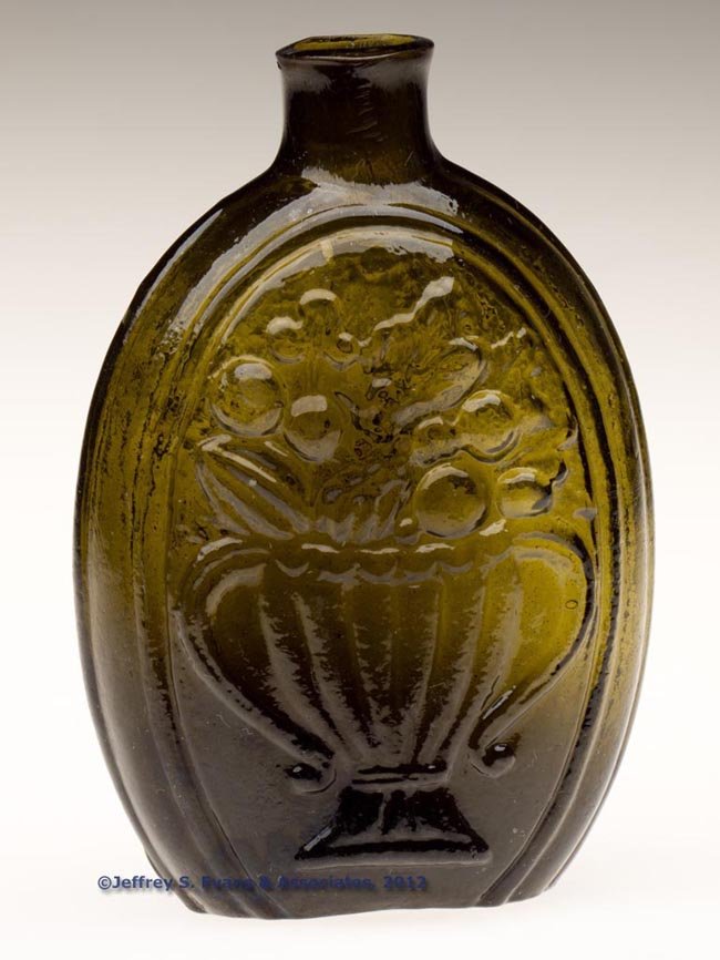 GIII-7 CORNUCOPIA - URN PICTORIAL FLASK: GIII-7 CORNUCOPIA - URN PICTORIAL FLASK, olive green, half-pint, sheared mouth, rough pontil mark. New England, probably Keene or Coventry Glass Works. 1825-1850. 5 3/8" H. Provenance: Collection of G