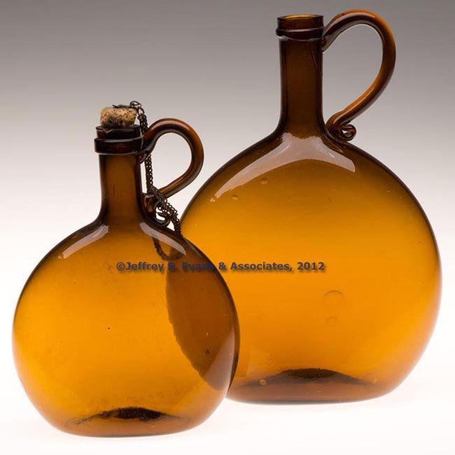 TWO FREE-BLOWN HANDLED CHESTNUT-FORM FLASKS: TWO FREE-BLOWN HANDLED CHESTNUT-FORM FLASKS, medium amber, each flattened slightly ovoid body with medium neck and flat ring applied below the plain mouth, applied handle at neck, and slight kick-up b
