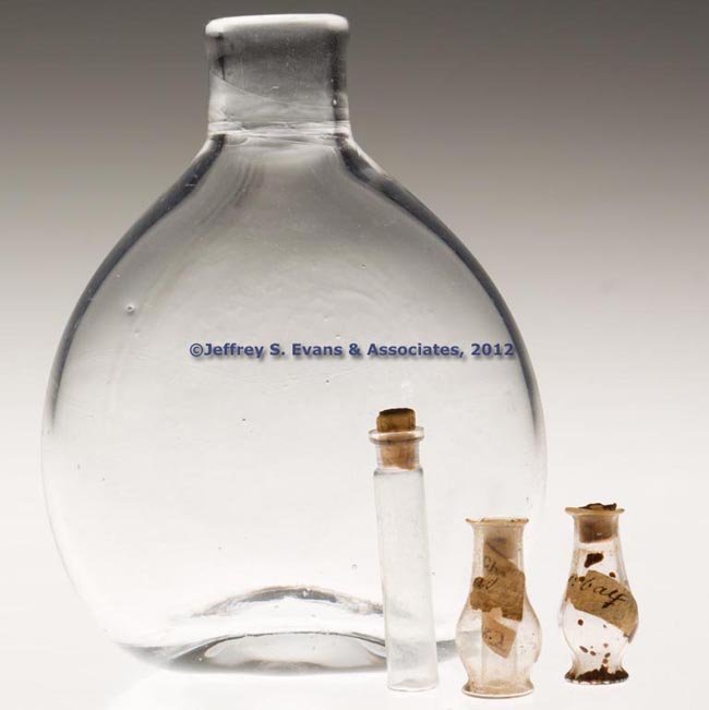 ASSORTED BLOWN BOTTLES, LOT OF FOUR: ASSORTED BLOWN BOTTLES, LOT OF FOUR, colorless, comprising a small unpatterned pocket bottle with rough pontil mark and three miniature/toy apothecary bottles, two with original labels. 19th century. 