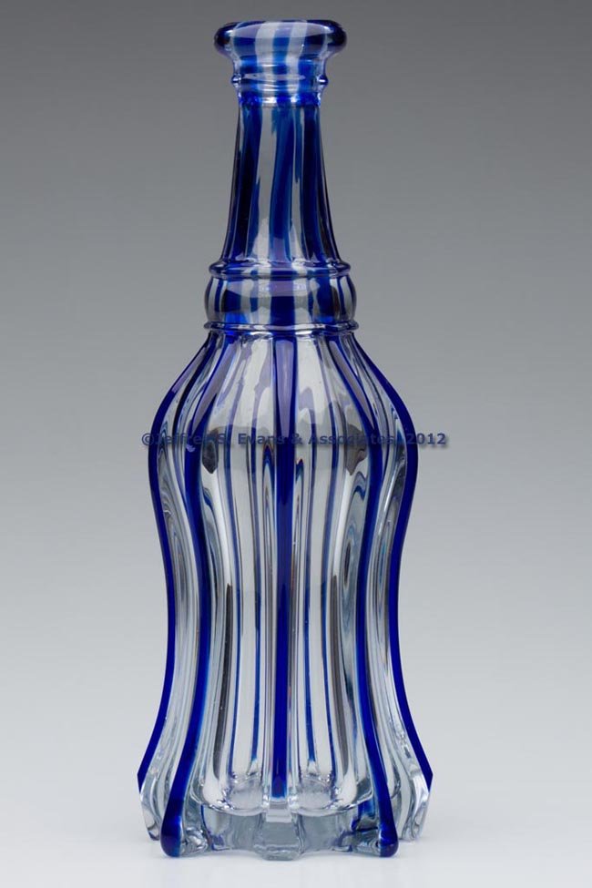 PILLAR-MOLDED QUART BAR DECANTER: PILLAR-MOLDED QUART BAR DECANTER, colorless with applied blue ribbons from base to mouth, tall petticoat form with eight protruding ribs, applied wide convex neck ring, and a rounded bar lip ground on