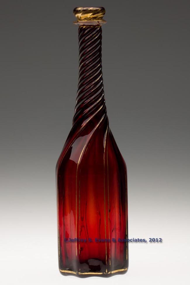 SWIRLED PILLAR-MOLDED PINT DECANTER: SWIRLED PILLAR-MOLDED PINT DECANTER, ruby cased in colorless with gilt decoration, cylinder form with eight ribs tightly swirled to the right on the tapered neck, applied collar below the rounded lip,