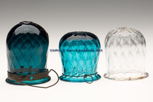 THREE PATTERN-MOLDED CHRISTMAS LIGHTS: THREE PATTERN-MOLDED CHRISTMAS LIGHTS, two shades of teal/peacock green and colorless, each molded with expanded diamonds, folded rim and rough pontil mark, two with hangers. 1830-1870. 2 3/4" to 3 1/