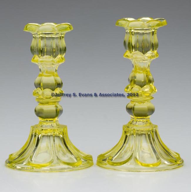 PAIR OF PRESSED PETAL AND LOOP CANDLESTICKS: PAIR OF PRESSED PETAL AND LOOP CANDLESTICKS, bright canary yellow, each six-petal socket with a hexagonal extension, raised on a hexagonal knop and seven-loop circular base with rough pontil mark, waf