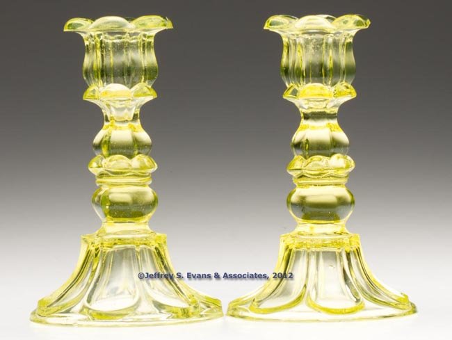 PAIR OF PRESSED PETAL AND LOOP CANDLESTICKS: PAIR OF PRESSED PETAL AND LOOP CANDLESTICKS, canary yellow, each six-petal socket with a hexagonal extension, raised on a hexagonal knop and seven-loop circular base with rough pontil mark, wafer cons