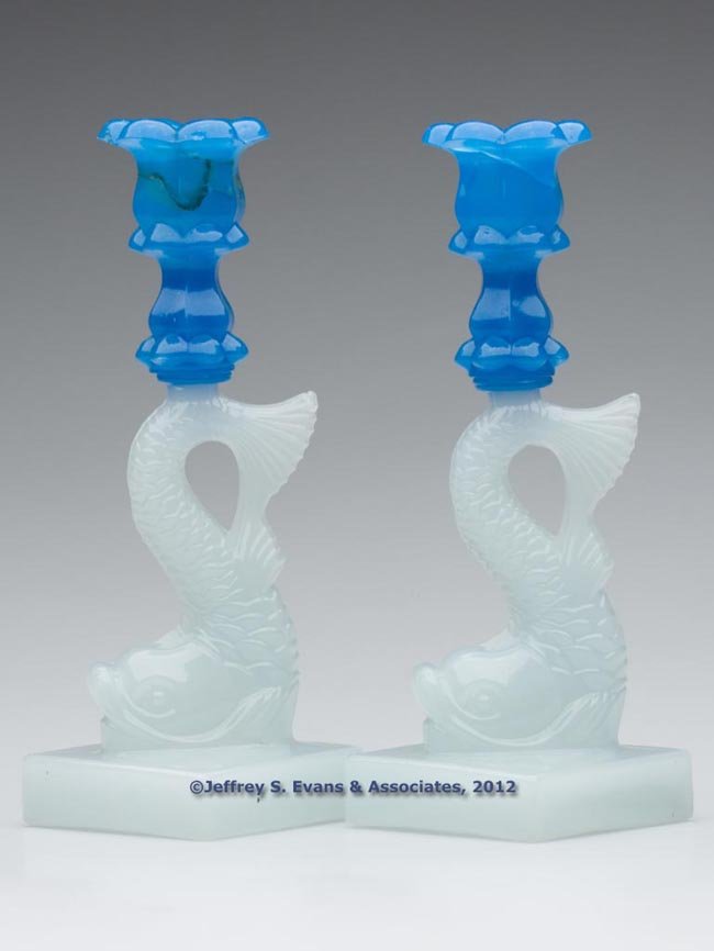 PAIR OF PRESSED DOLPHIN SINGLE-STEP CANDLESTICKS: PAIR OF PRESSED DOLPHIN SINGLE-STEP CANDLESTICKS, shiny translucent starch blue above alabaster/clambroth, each six-petal socket with lower extension, raised on a large dolphin-form standard and squar