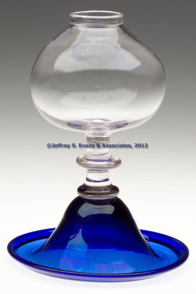 FREE-BLOWN SAUCER-BASE WHALE OIL LAMP: FREE-BLOWN SAUCER-BASE WHALE OIL LAMP, colorless globular font raised on an applied colorless medial-button stem and cobalt blue conical saucer-edge base with folded rim and rough pontil mark. Boston 