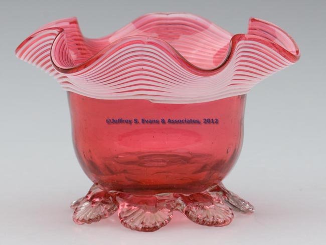 VICTORIAN GLASS OPEN SALT: VICTORIAN GLASS OPEN SALT, cranberry bowl with applied opaque white threading around the gauffered rim, raised on seven applied colorless petal feet, rough pontil mark. Probably England. 1875-1900. 2 