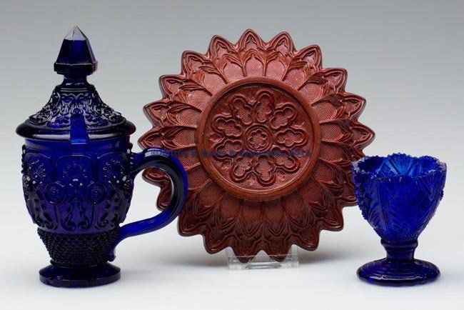 ASSORTED FOREIGN PRESSED LACY TABLE ARTICLES, LOT: ASSORTED FOREIGN PRESSED LACY TABLE ARTICLES, LOT OF THREE, comprising a slightly marbled opaque brick red plate, a deep brilliant cobalt condiment cup with cover, and a swirling cobalt egg cup. Franc