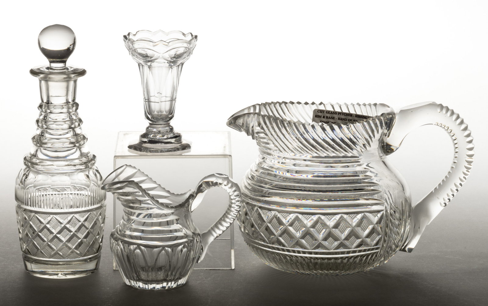 ASSORTED ANGLO-IRISH CUT GLASS ARTICLES, LOT OF FOUR: ASSORTED ANGLO-IRISH CUT GLASS ARTICLES, LOT OF FOUR, colorless lead glass, comprising a strawberry diamond band cruet with a period stopper and pitcher with applied handle, a Gothic Arches creamer, a