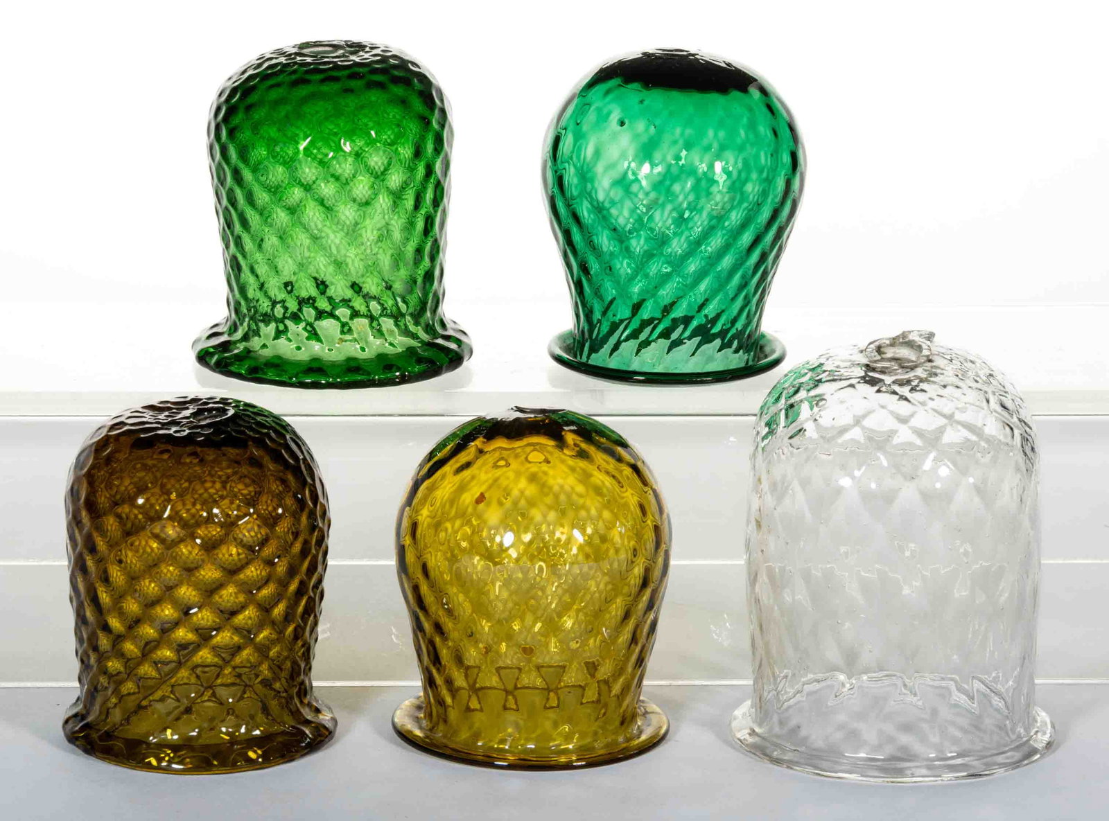 DIAMOND-PATTERN MOLDED GLASS CHRISTMAS LIGHTS, LOT OF FIVE: DIAMOND-PATTERN MOLDED GLASS CHRISTMAS LIGHTS, LOT OF FIVE, comprising a colorless, two amber, and two emerald green examples. Fourth quarter 19th/first quarter 20th century. 3" to 3 3/4&quo
