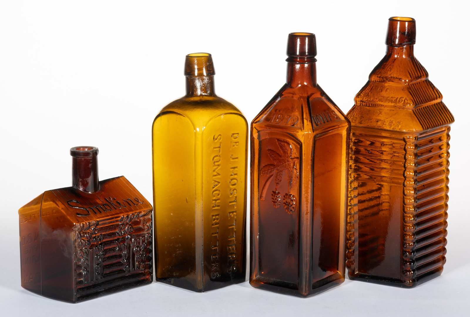 ASSORTED GLASS BITTER'S BOTTLES, LOT OF FOUR: ASSORTED GLASS BITTER'S BOTTLES, LOT OF FOUR, amber, including a "SMOKINE", "DOYLES", and a "DRAKE'S PLANTATION". Various makers. Fourth quarter 19