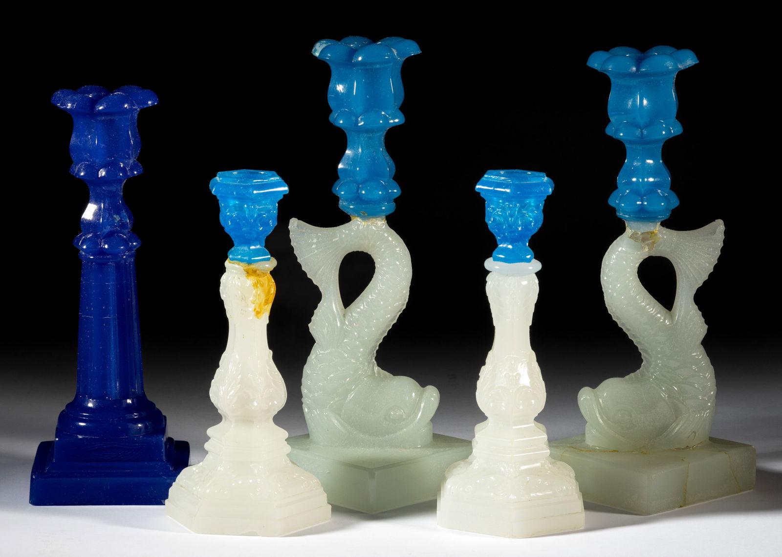 ASSORTED PRESSED GLASS CANDLESTICKS, LOT OF FIVE: ASSORTED PRESSED GLASS CANDLESTICKS, LOT OF FIVE, alabaster/clambroth and starch blue, comprising two small-size Acanthus, a pair of single-step Dolphin examples, and a Columnar example. Boston &