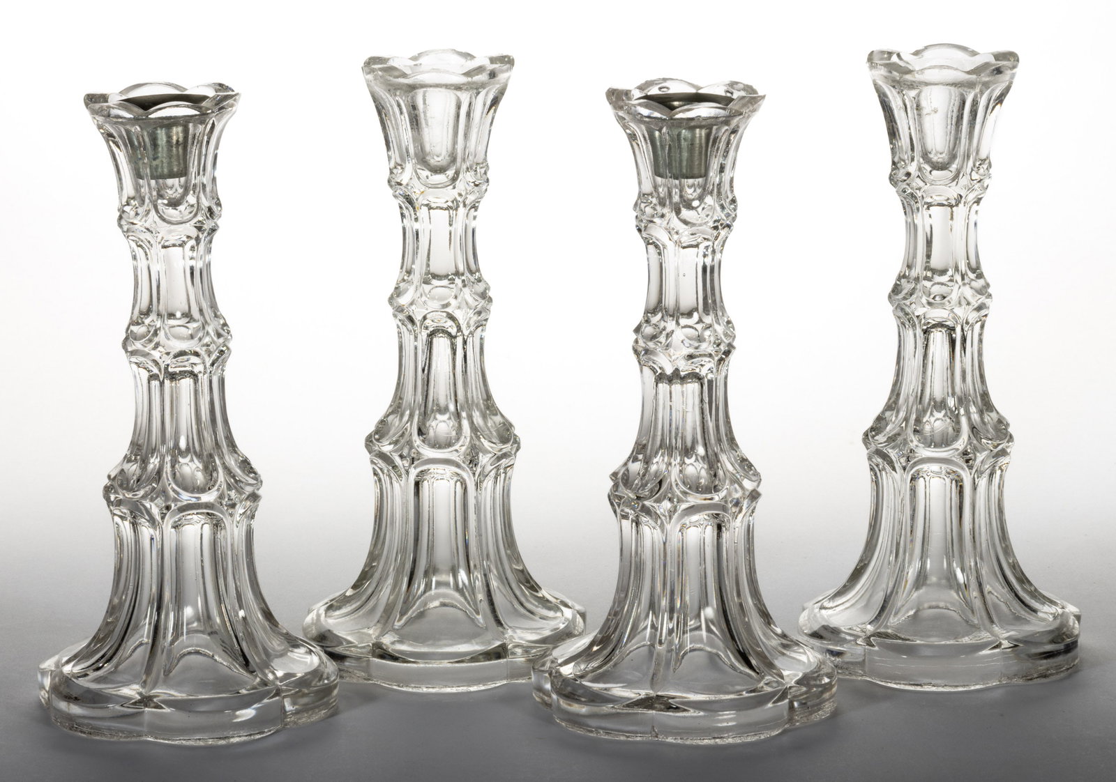 PRESSED EXCELSIOR TWO PAIRS OF CANDLESTICKS: PRESSED EXCELSIOR TWO PAIRS OF CANDLESTICKS, colorless lead glass, with two having a period Britannia socket insert. Pittsburgh area. Third quarter 19th century. 8 1/4" H, 4" DOA bases.