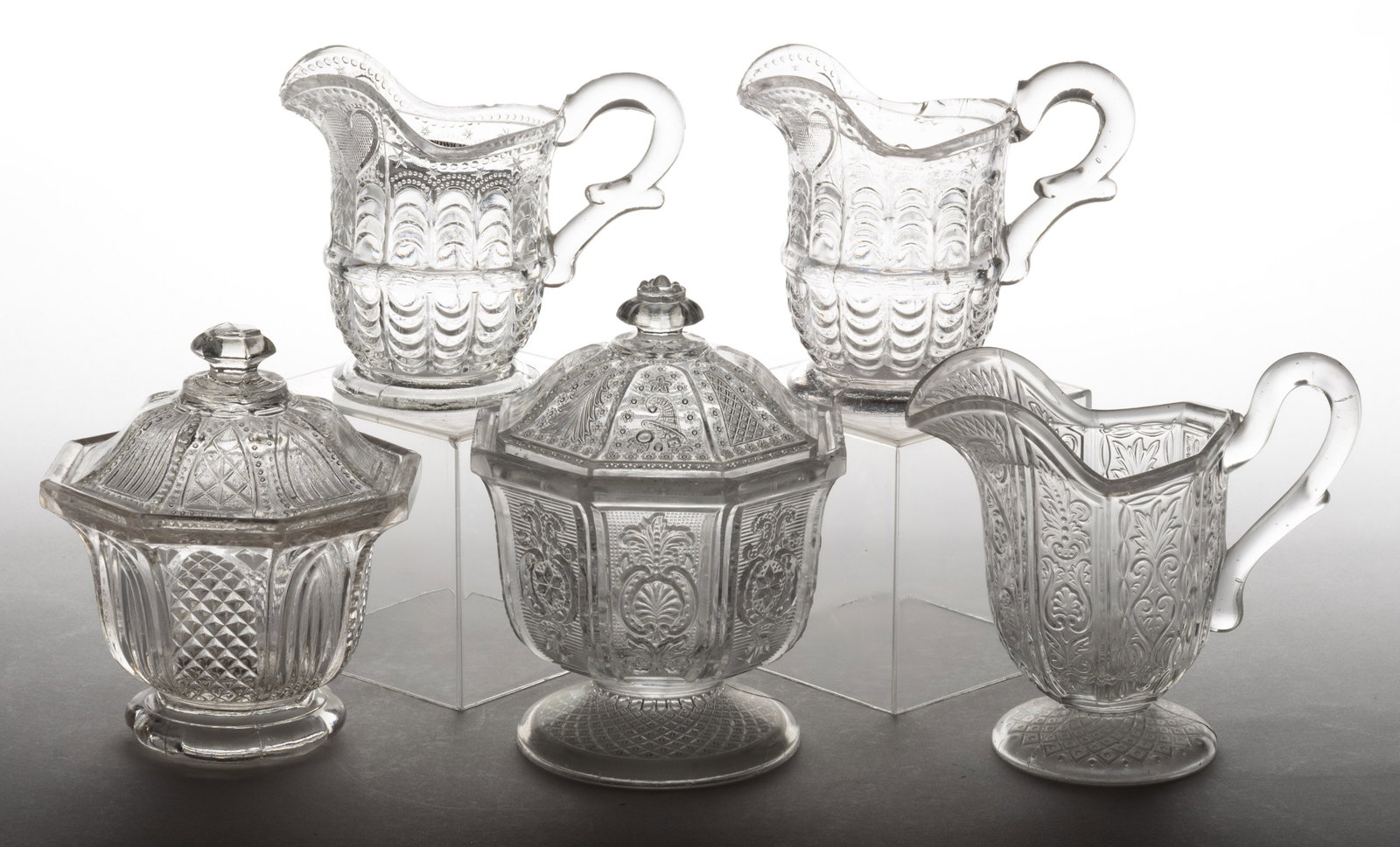 PRESSED LACY GLASS TABLE ARTICLES, LOT OF FIVE: PRESSED LACY GLASS TABLE ARTICLES, LOT OF FIVE, colorless, comprising a California covered sugar bowl and creamer, a Gothic Arch covered sugar bowl with a scalloped foot, and two Heart and Scale cream
