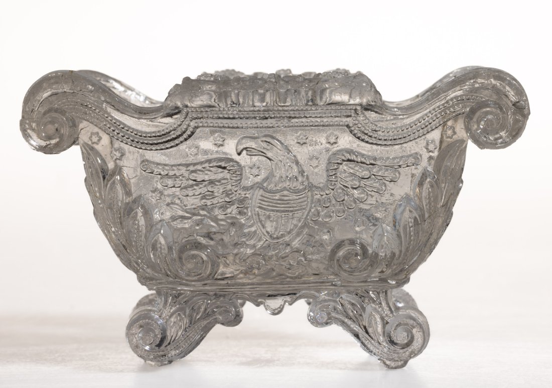 EE-7 EAGLE PRESSED OPEN SALT: EE-7 EAGLE PRESSED OPEN SALT, colorless, Empire sofa form raised on four scrolled feet, very faint stippling and diamonds under base. Rare. Probably Boston & Sandwich Glass Co. 1830-1845. 2 1/4" H, 2 