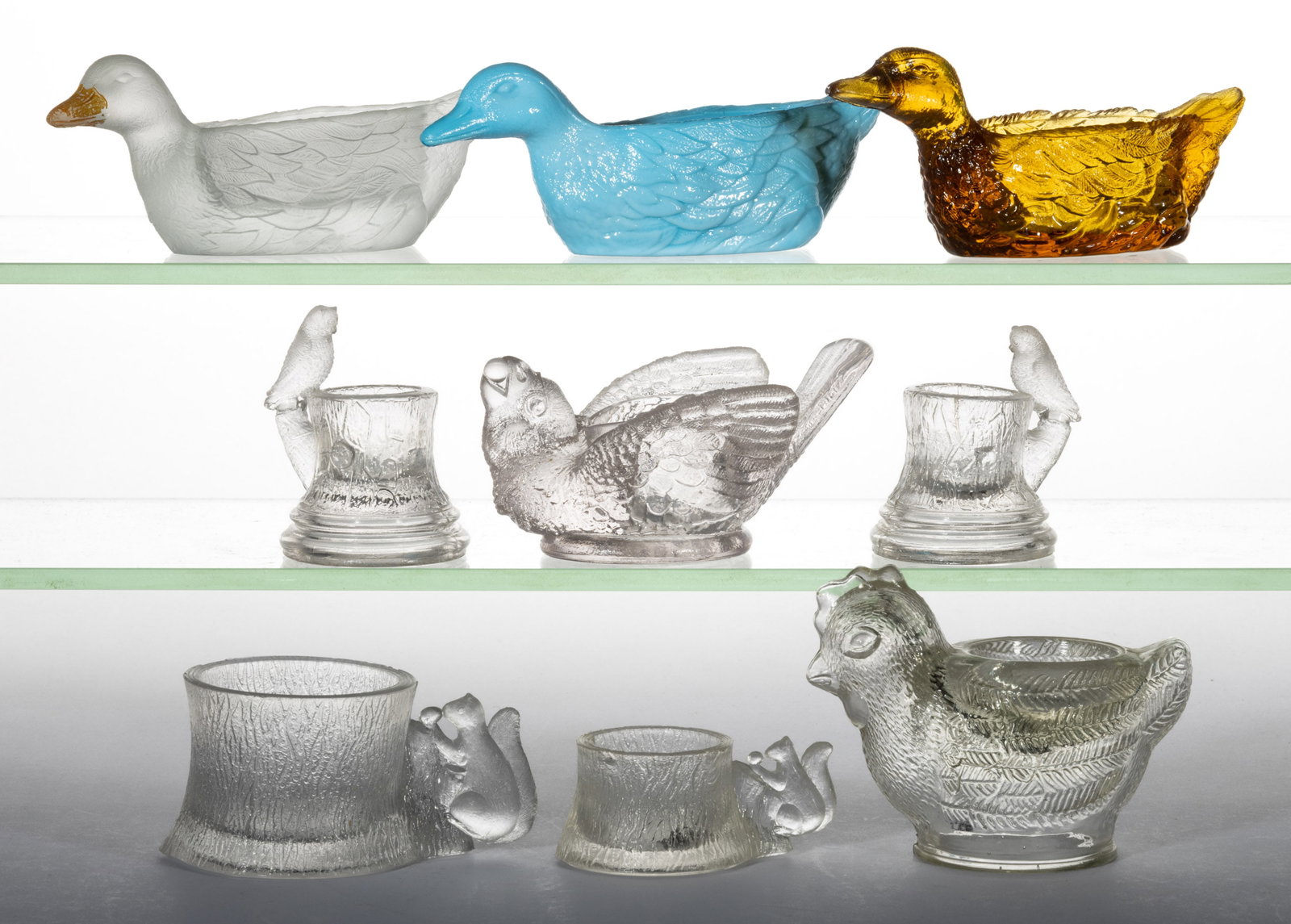 PRESSED NOVELTY FIGURAL ANIMAL GLASS OPEN SALTS, LOT OF NINE: PRESSED NOVELTY FIGURAL ANIMAL GLASS OPEN SALTS, LOT OF NINE, colorless and opaque blue, and amber, including three Ducks, a Bird with Berry, and two Owl and Stump. Various makers. Fourth quarter