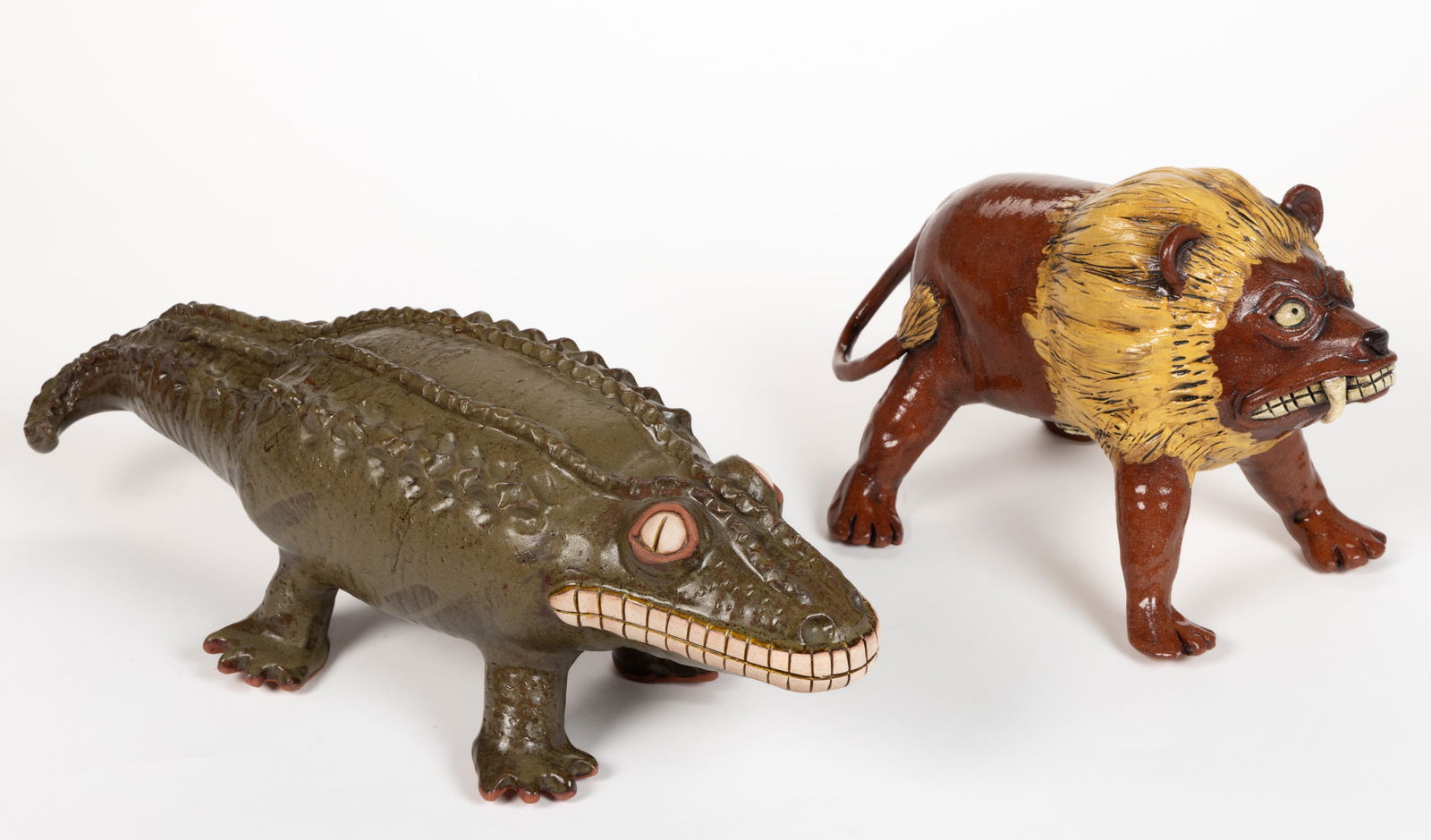 SIGNED KAREN LABARGA EARTHENWARE / REDWARE ANIMAL FIGURES, LOT OF TWO: SIGNED KAREN LABARGA EARTHENWARE / REDWARE ANIMAL FIGURES, LOT OF TWO, each standing with expressive features, comprising a lion with protruding fangs and an alligator with a toothy grin. Each signed