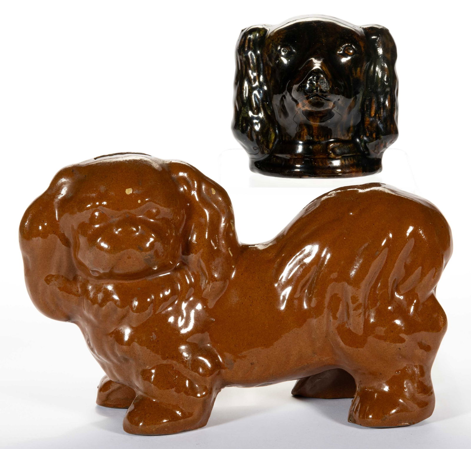 AMERICAN EARTHENWARE / REDWARE DOG FIGURAL BANKS, LOT OF TWO: AMERICAN EARTHENWARE / REDWARE DOG FIGURAL BANKS, LOT OF TWO, comprising a mottled-glaze King Charles Spaniel head and a lead-glazed full-body Spaniel. Late 19th/first half 20th century. 4" and 6