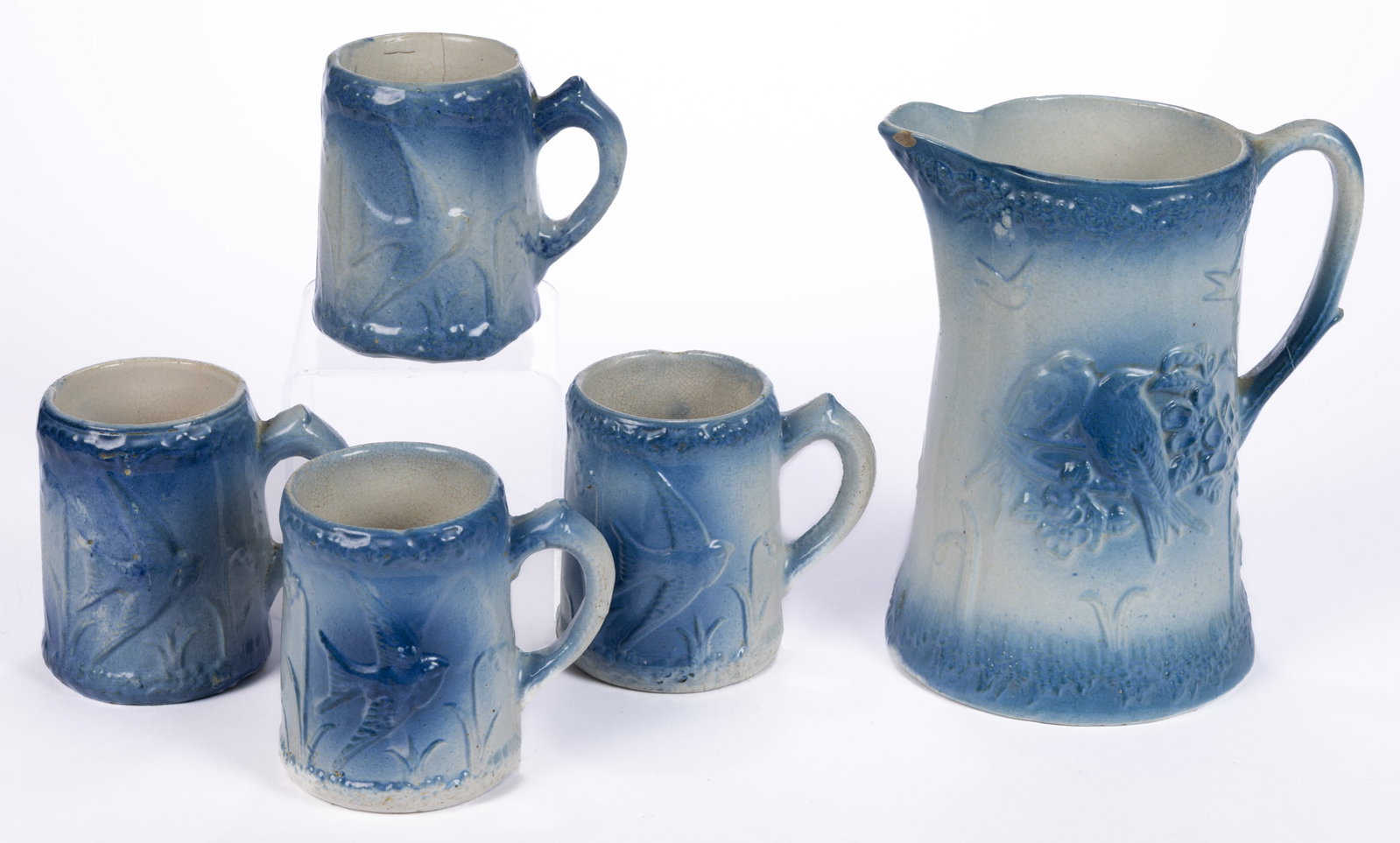 AMERICAN BLUE AND WHITE FLYING BIRDS STONEWARE FIVE-PIECE PITCHER AND MUGS SET: AMERICAN BLUE AND WHITE FLYING BIRDS STONEWARE FIVE-PIECE PITCHER AND MUGS SET, comprising a pitcher featuring four soaring birds above flowers to one side and Love Birds pattern to reverse and e