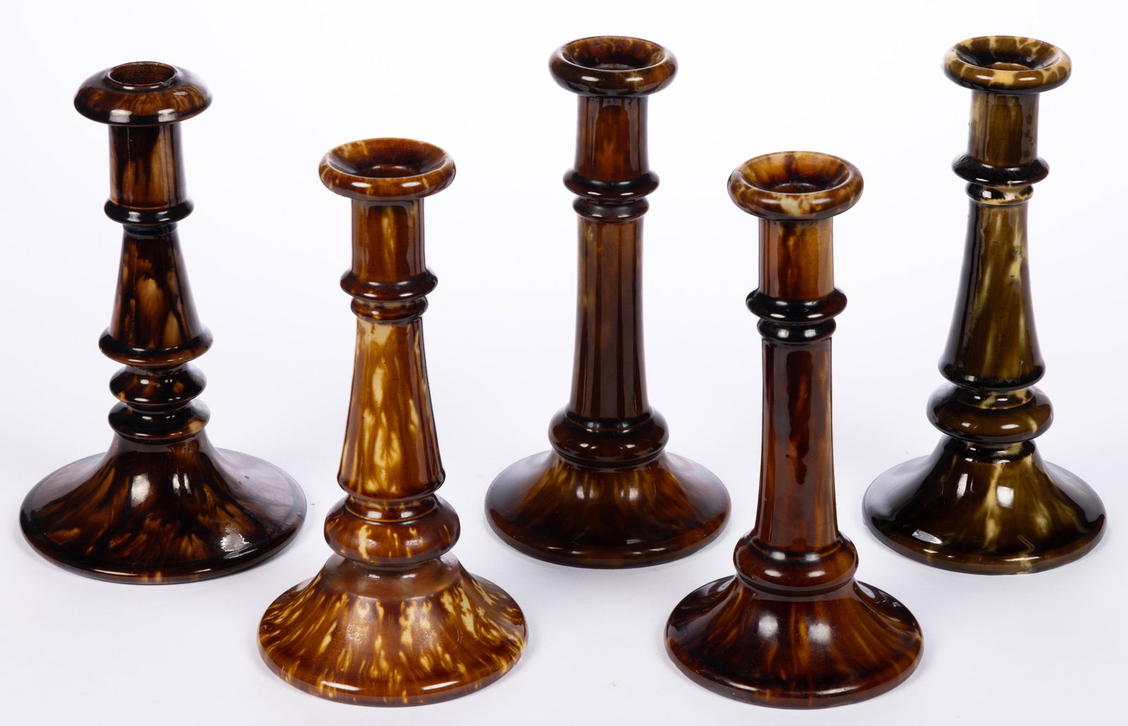 AMERICAN BENNINGTON ATTRIBUTED ROCKINGHAM-GLAZED POTTERY CANDLESTICKS, LOT OF FIVE: AMERICAN BENNINGTON ATTRIBUTED ROCKINGHAM-GLAZED POTTERY CANDLESTICKS, LOT OF FIVE, mottled brown glaze, comprising one pair, one near pair, and one single. Unmarked. Probably Lyman Fenton &