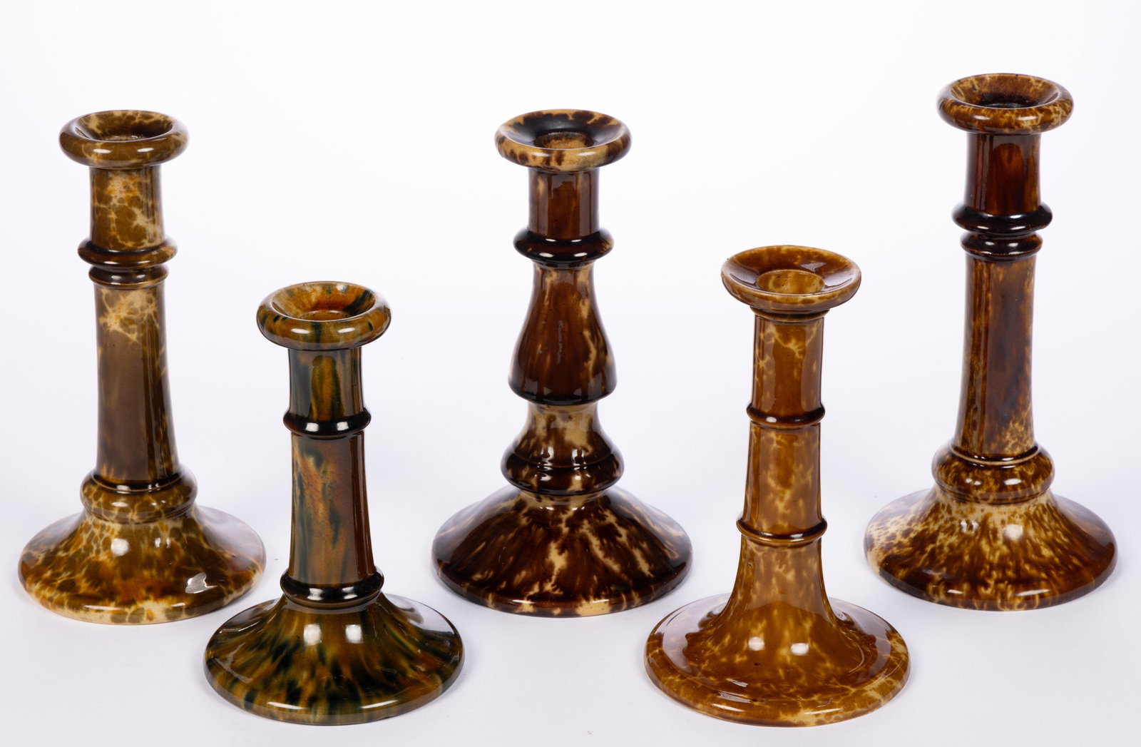 AMERICAN BENNINGTON ATTRIBUTED ROCKINGHAM-GLAZED POTTERY CANDLESTICKS, LOT OF FOUR: AMERICAN BENNINGTON ATTRIBUTED ROCKINGHAM-GLAZED POTTERY CANDLESTICKS, LOT OF FOUR, comprising two examples with flint enamel glazes including one with mottled orange and brown glaze and one exam